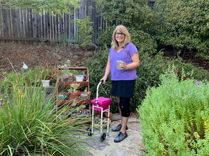 Woman standing with Giraffe Rolling Cane holding a plant in her yard